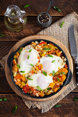 Shakshouka in frying pan. Fried eggs with vegetables, tomato, pepper, pumpkin and onion. Top view