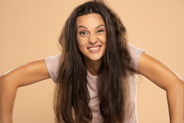 Funny smiling beautitul woman with messy long hair on a beige background