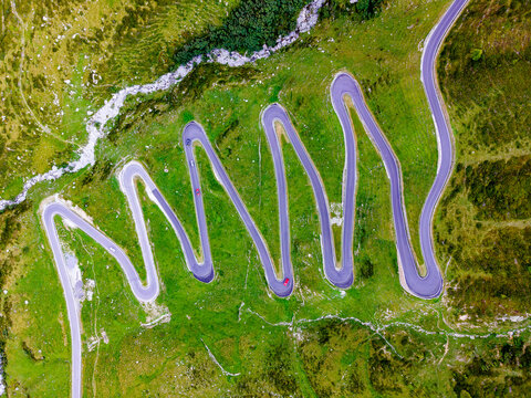 Drone shot on zig zag of pass road with curves in the mountains Spl&uuml;genpass Monte de Spluga at the border between Switzerland and Italy