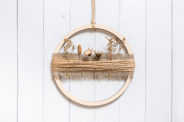 Handmade home rustic decor from a wooden circle and dried flowers on wooden background.