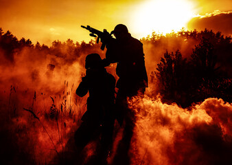 United States Marines in action. Military action, desert battlefield, smoke grenades., fire and explosions. Sun setting, dark silhouettes in the desert