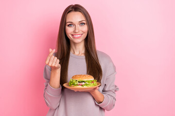 Portrait of positive nice person hold burger arm fingers demonstrate korean love symbol isolated on...