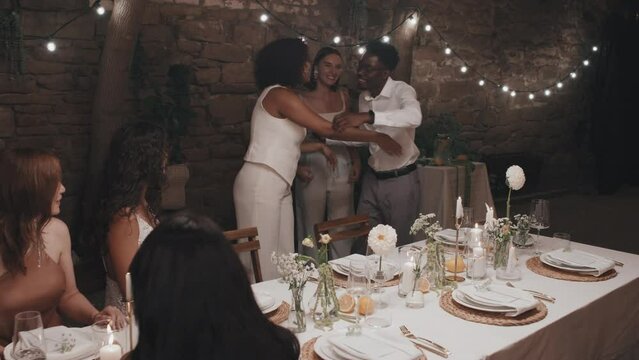 Young Black man and Caucasian woman coming to wedding party in evening in modern restaurant, newlyweds greeting them