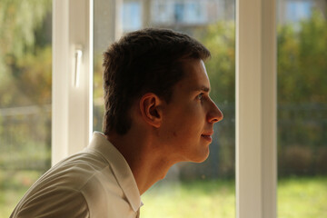 Young man in white shirt profile face on a window background. Pavel Kubarkov, my face on a window background. Photo was taken 8 October 2022 year, MSK time in Russia. - 537259719