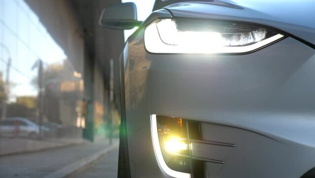 Close up of headlights of modern car. Switching of automobile LED head lights. New auto headlamp. Front of vehicle with flashing lamp. Detail view