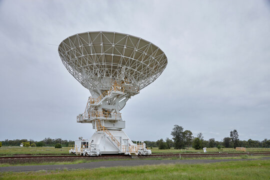 close up shot of a white radio telescope in a filed on a cloudy day