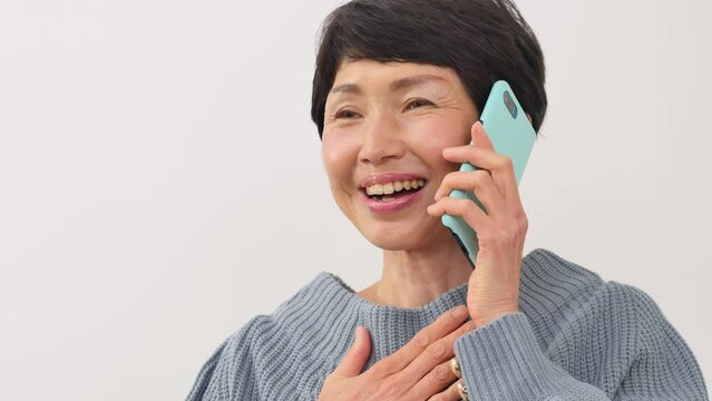 嬉しそうにスマホで電話する中年女性　白背景