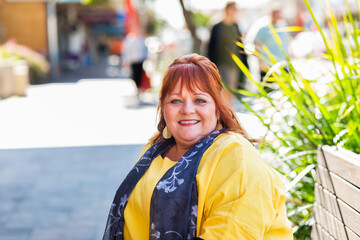 Headshot of happy smiling middle age woman wearing yellow in urban setting