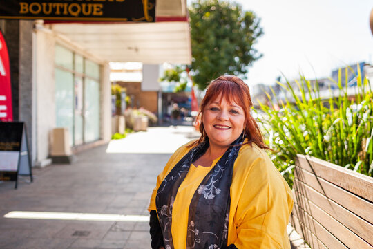 Headshot of happy smiling middle age woman wearing yellow in urban setting