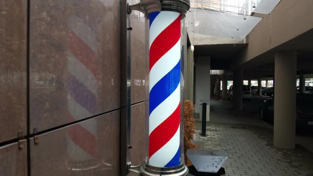 Motion of barbershop pole spinning at barber shop outdoors. Advertising design on the facade of the building at the entrance.