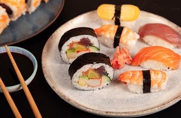 Sushi Set sashimi and sushi rolls served on a plate with saucers and soy sauce