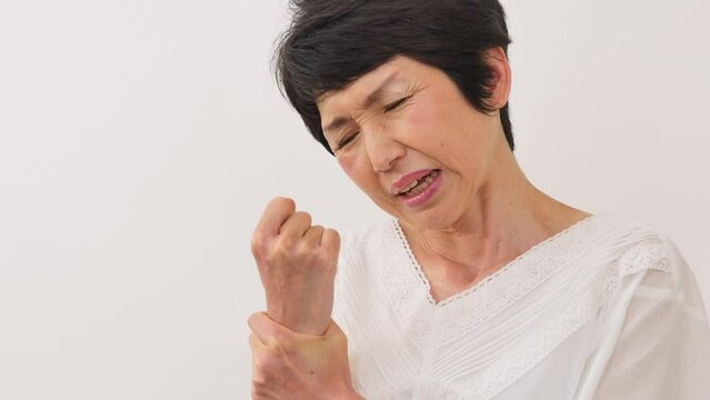 白背景で手首が痛い中年女性