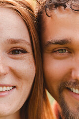 Vertical cropped portrait of young beautiful couple looking at the camera and smiling, Half face crop.