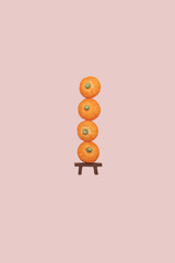 Candy sugar orange pumpkin stack on a bench on pink background with copy space. Minimal halloween holiday celebration horror concept. Autumn party pattern idea.