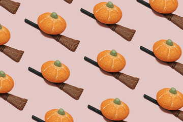 Candy sugar orange pumpkin on a witch broom stick on pink background with copy space. Minimal halloween holiday celebration horror concept. Autumn party pattern idea.