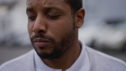 Fototapeta premium One anxious young African American man in distress closeup face. Portrait of a black person with worried preoccupied emotion