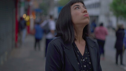 Fototapeta premium Stressed young hispanic woman standing in urban street fidgeting with hands. Preoccupied South American adult girl feeling nervous and preoccupation