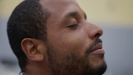 Obraz premium Spiritual young African American man closing eyes in contemplation. Brazilian person opening eye to sky with HOPE and FAITH