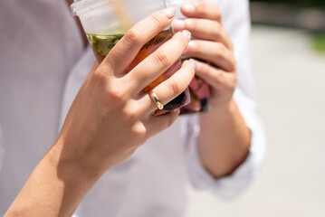 newlyweds with cocktails in their hands. close-up of the hand and ring. summer drink