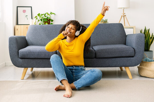 Happy african woman singing in hand microphone while relaxing at home - Happiness lifestyle concept