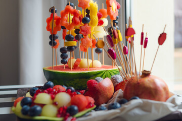 Fruit salad for a child's birthday. Various fruits are put on toothpicks and hammered into half of...