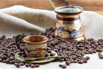 Vintage copper cup with coffee turk and roasted coffee beans on sackcloth