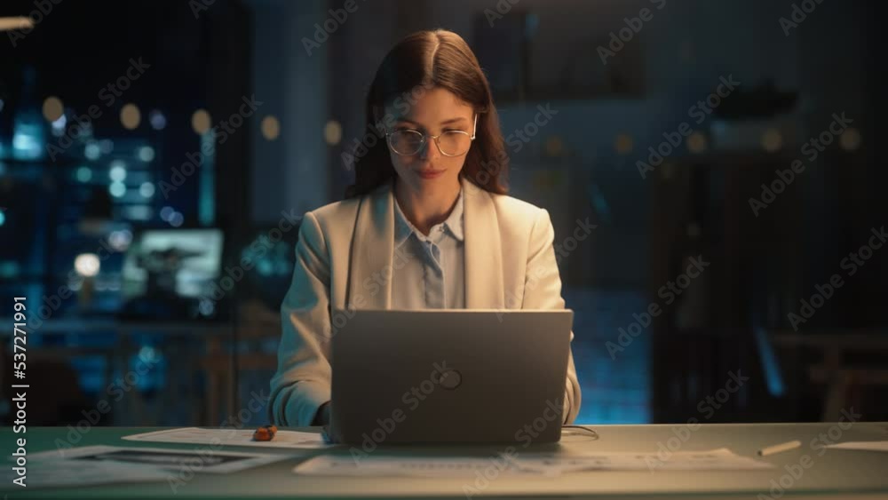 Poster stylish female in glasses working on laptop computer in a company office in the evening. young manag