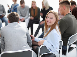 smiling young woman sitting in a circle of colleagues