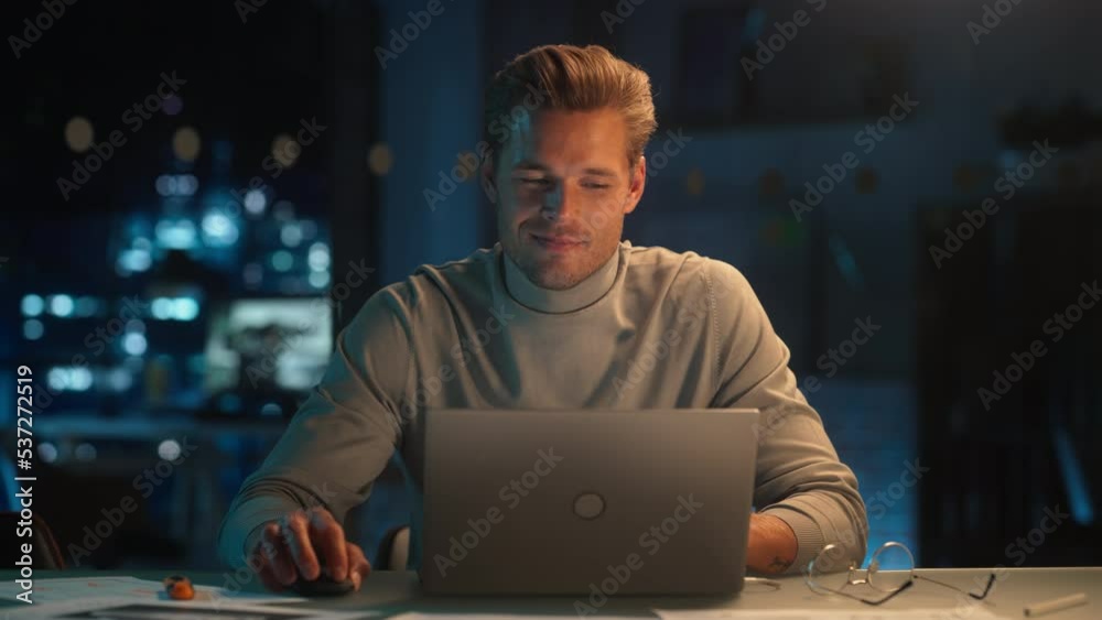 Poster portrait of a stylish male working on laptop computer in a company office in the evening. young mana