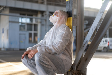 Despair healthcare worker in white covid protective overalls. Tired Male caucasian doctor in depression during coronavirus pandemic