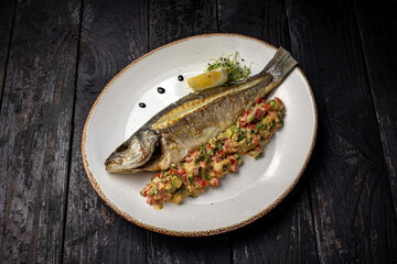 delicious grilled fish with a side dish. On a dark background
