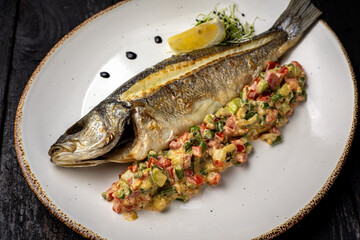 delicious grilled fish with a side dish. On a dark background
