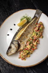 delicious grilled fish with a side dish. On a dark background
