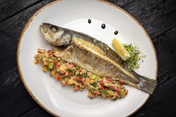 delicious grilled fish with a side dish. On a dark background
