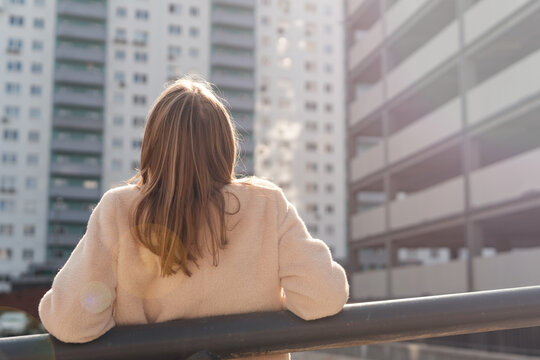 View From Behind Of Happy Woman Resting In The City. Female Wearing Coat And Relaxing In The City