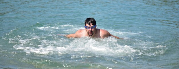 a man in swimming goggles swims in the water