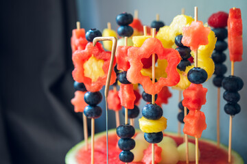 Colorful fruit dessert for a child's birthday. Various shapes of fruit are put on toothpicks....
