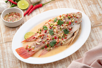 Steamed Red Tilapia Fish with Spicy Lemon Sauce in white plate