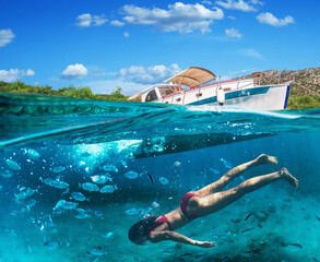 Woman diver is snorkeling on a beautiful sea beach. The bottom half of the picture is occupied by...