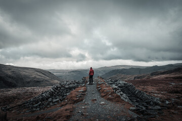 Man standing on the peak of a mountain gazing at the view on a gloomy day