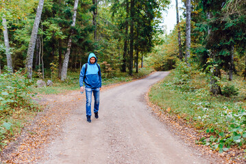 Obraz premium A middle age male hiking with a backpack.Man walks along the autumn forest path way.A healthy lifestyle in nature.