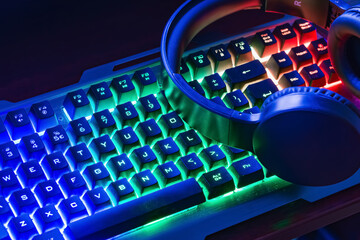 Pro gaming illuminated desk, headset, keyboard, computer neon lights. Cyber sport equipment laying on desktop, ready for online video gaming.Dark shot. © ARVD73
