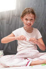 Little school girl with chickenpox drawing on white board in kids' room, antiseptic cream applied...