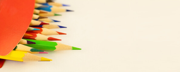 Multi-colored pencils in a red box. Back to school. Background with colored wooden pencils and copy...