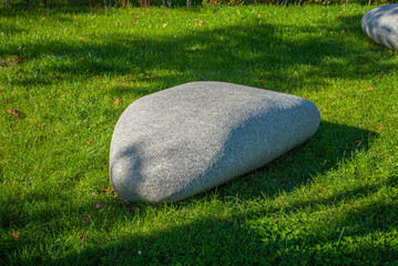 gray granite boulder on a green lawn