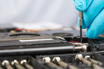 Hands of a technician repairing a broken laptop computer. Laptop repair service. Engineer fixing broken notebook. Computer technology. Laptop disassembling in repair shop, close-up.