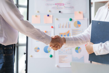 Shaking hands between business man and woman start up team in boardroom.