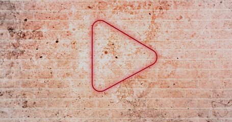 Composite of digital illuminated red play button icon against grunge brick wall, copy space