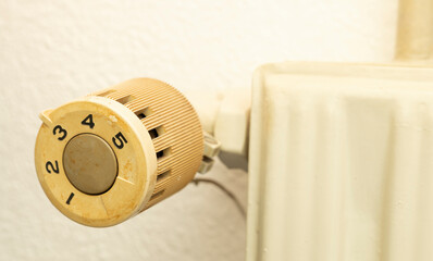 Closeup of old radiator heating in house with white wall background.  Knob with number to be adjust...