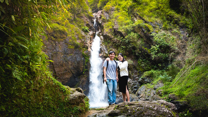 Asian woman standing enjoy with Jogkradin Waterfall background in Kanchanaburi , Thailand